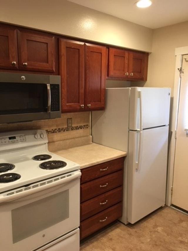 kitchen featuring white appliances, light countertops, and backsplash