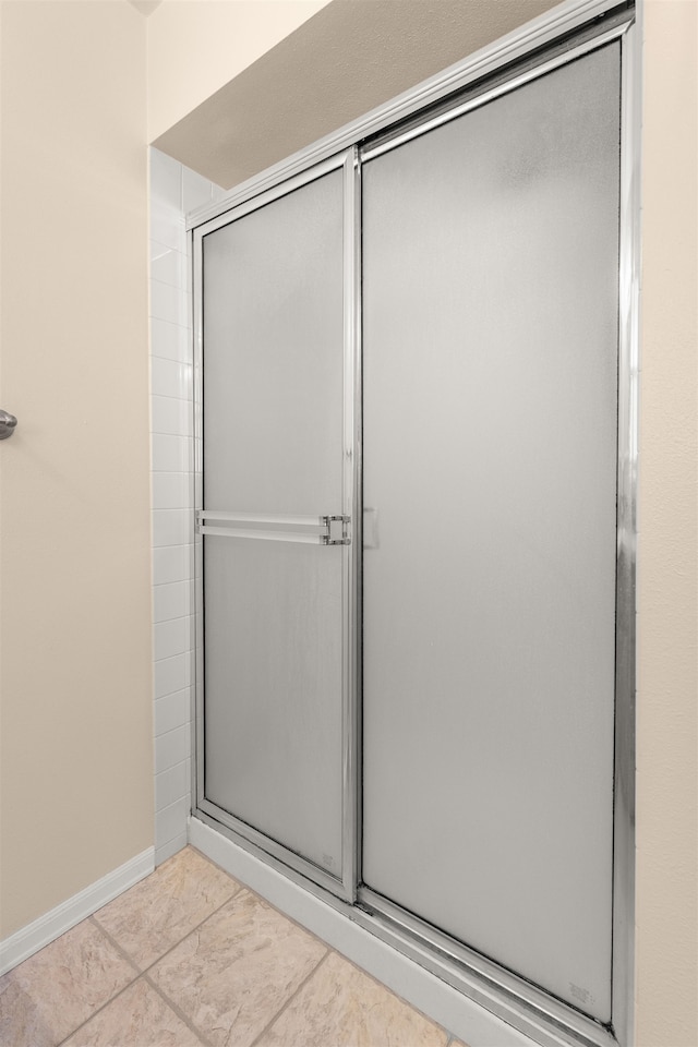 full bathroom with tile patterned flooring, an enclosed shower, and baseboards