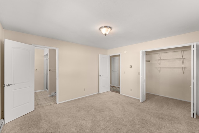 unfurnished bedroom with a closet, light colored carpet, baseboards, and baseboard heating