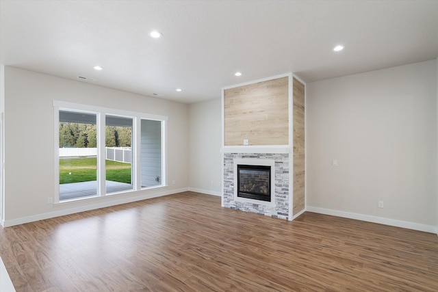 unfurnished living room featuring recessed lighting, a fireplace, baseboards, and wood finished floors