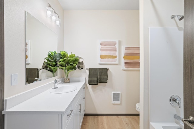 bathroom with bathtub / shower combination, toilet, wood finished floors, visible vents, and vanity