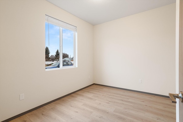 spare room with baseboards and light wood finished floors