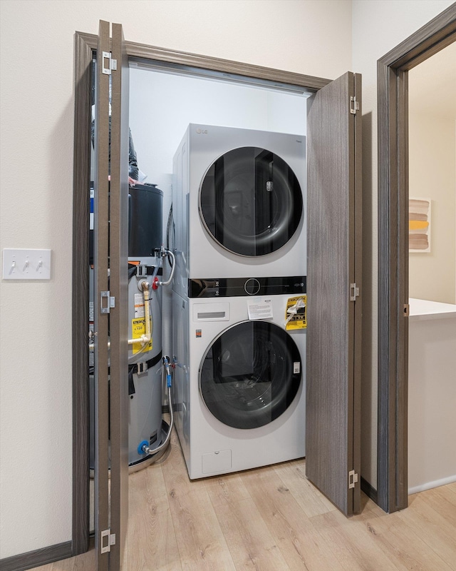 laundry area with laundry area, secured water heater, stacked washing maching and dryer, and wood finished floors