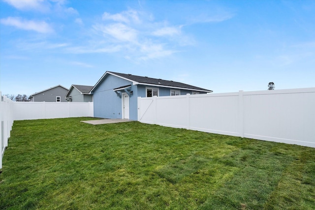 rear view of property featuring a fenced backyard and a lawn