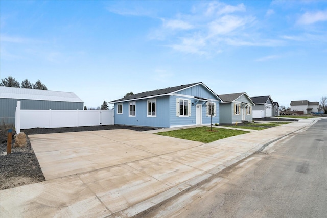 view of front of house featuring driveway, fence, a front lawn, and board and batten siding