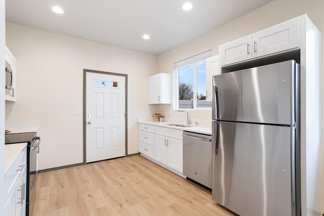 kitchen featuring light countertops, appliances with stainless steel finishes, a sink, and white cabinetry