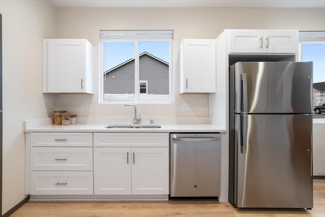 kitchen featuring stainless steel appliances, light countertops, white cabinets, and a sink