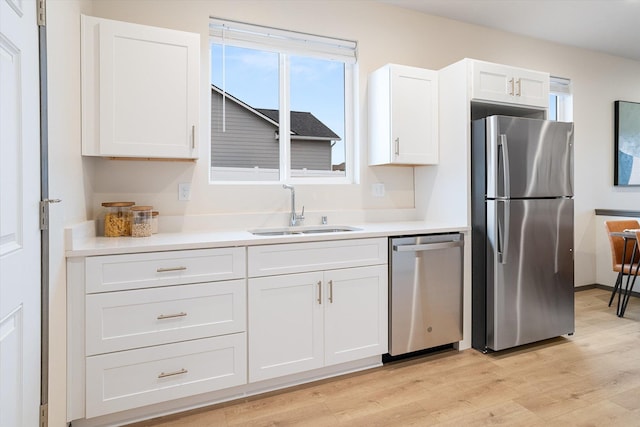 kitchen with appliances with stainless steel finishes, white cabinets, a sink, and light countertops