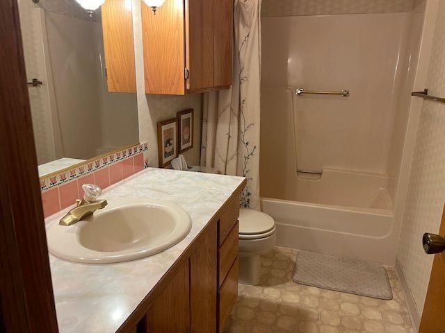 bathroom with vanity, toilet, and shower / bath combo with shower curtain