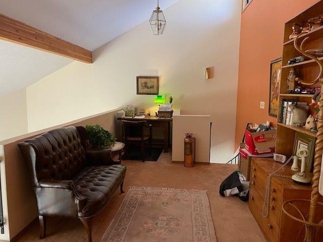 living area with lofted ceiling with beams and carpet