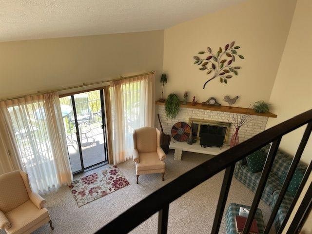 living room featuring carpet flooring, plenty of natural light, a textured ceiling, and a fireplace