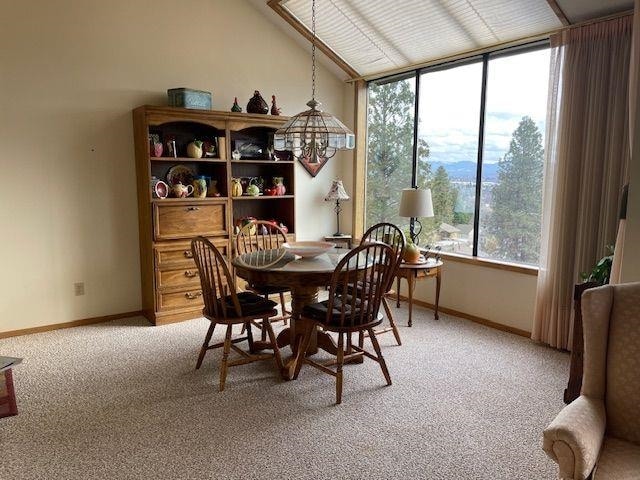 dining room featuring light carpet, baseboards, and vaulted ceiling