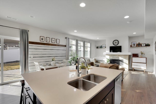 kitchen featuring visible vents, a glass covered fireplace, a sink, light countertops, and stainless steel dishwasher