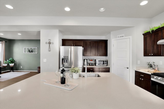 kitchen with appliances with stainless steel finishes, light countertops, a sink, and recessed lighting