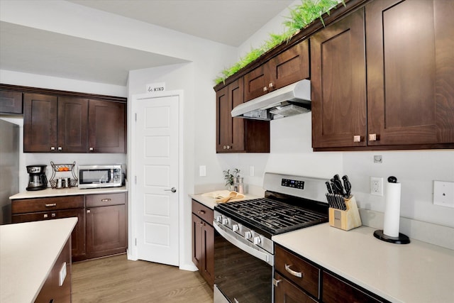 kitchen featuring light wood-type flooring, under cabinet range hood, stainless steel appliances, and light countertops