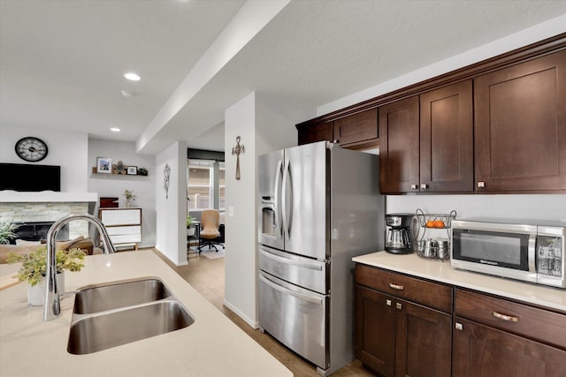 kitchen with a sink, open floor plan, light countertops, appliances with stainless steel finishes, and dark brown cabinets