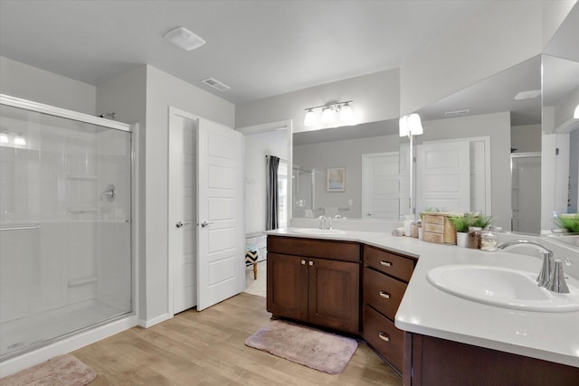 full bath with visible vents, a sink, a shower stall, and wood finished floors