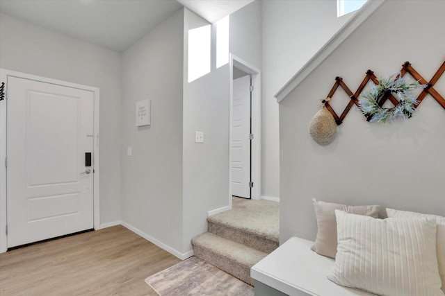 foyer with light wood-style flooring, stairway, and baseboards