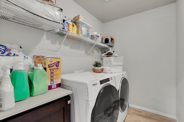 clothes washing area featuring washing machine and dryer, laundry area, baseboards, and light wood finished floors