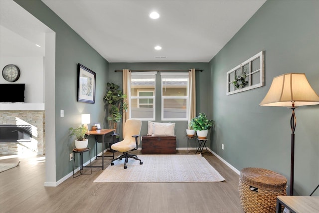 office space with recessed lighting, a fireplace, baseboards, and wood finished floors