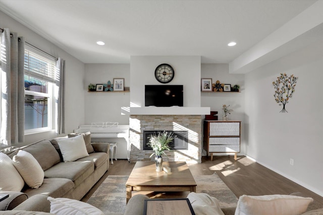 living room featuring recessed lighting, wood finished floors, and a stone fireplace