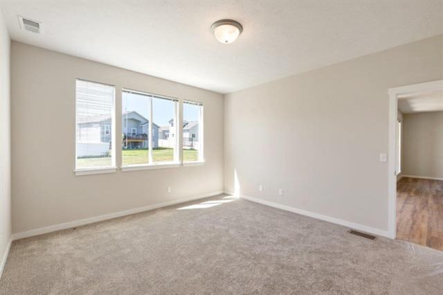 empty room featuring carpet floors, visible vents, and baseboards