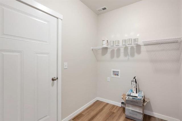 laundry area with laundry area, washer hookup, visible vents, baseboards, and light wood finished floors