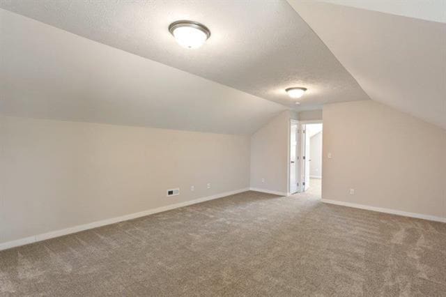 bonus room with visible vents, baseboards, carpet, vaulted ceiling, and a textured ceiling