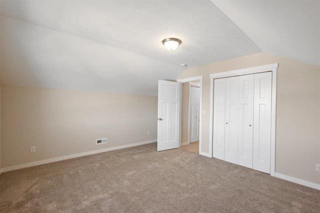 interior space with visible vents, baseboards, lofted ceiling, carpet flooring, and a closet