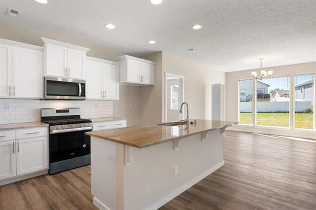 kitchen featuring stainless steel appliances, wood finished floors, a sink, and white cabinetry