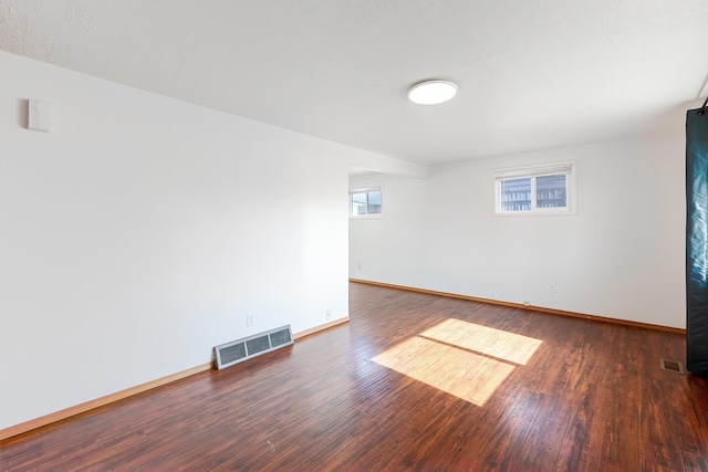 spare room with baseboards, visible vents, and wood finished floors