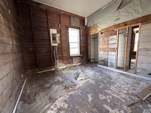 miscellaneous room with electric panel and wood walls