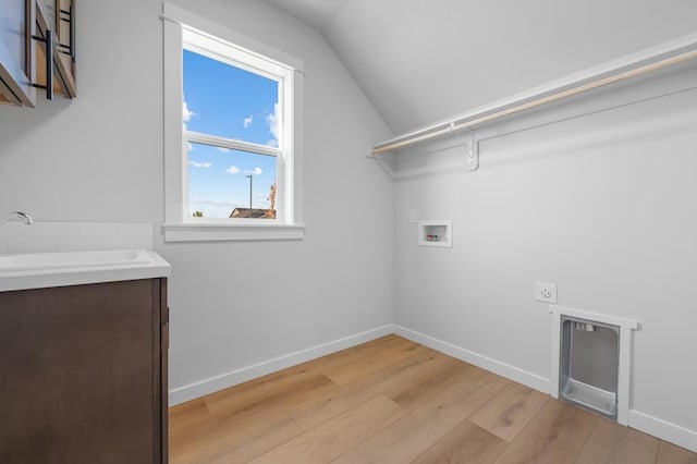 clothes washing area with hookup for a washing machine, light wood-style flooring, hookup for an electric dryer, a sink, and baseboards