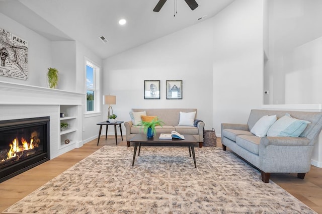 living room featuring recessed lighting, wood finished floors, visible vents, baseboards, and a glass covered fireplace