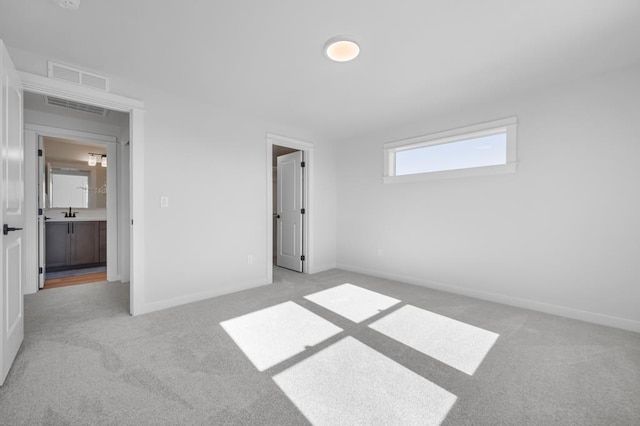 unfurnished bedroom with light carpet, a sink, visible vents, and baseboards