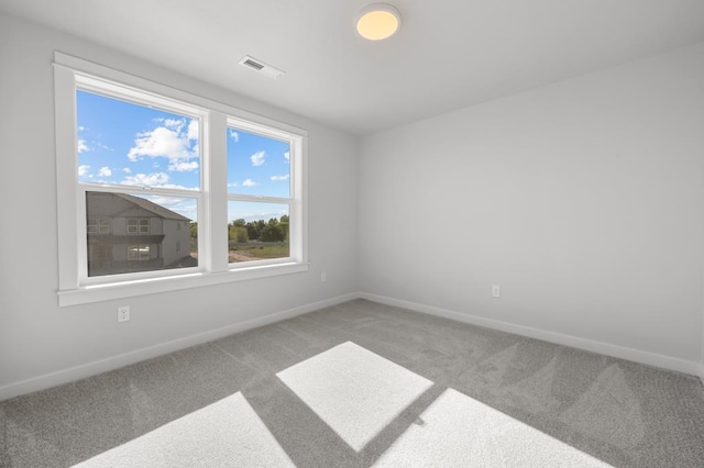 carpeted spare room featuring visible vents and baseboards