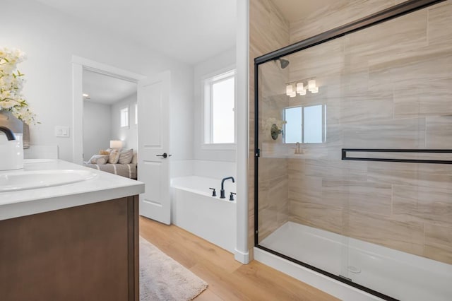 bathroom with wood finished floors, double vanity, a shower stall, and a bath