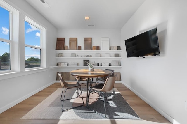 dining area with light wood-style flooring, visible vents, and baseboards