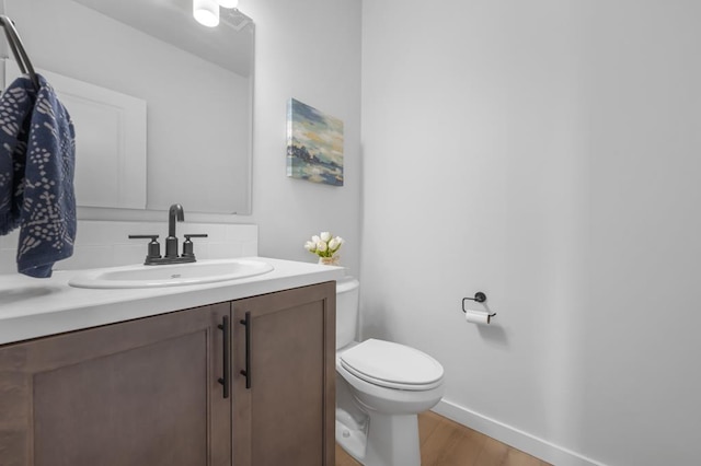 bathroom with toilet, baseboards, wood finished floors, and vanity