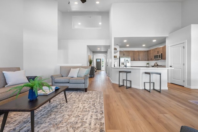 living area featuring ceiling fan, light wood-type flooring, a towering ceiling, and recessed lighting