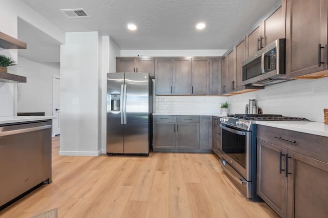 kitchen with stainless steel appliances, light countertops, visible vents, and light wood-style floors