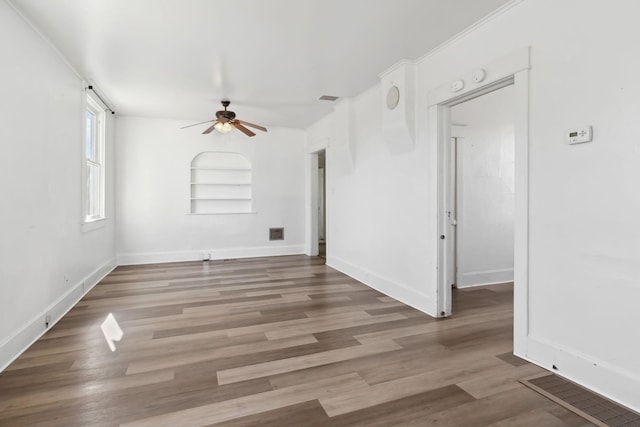 spare room with baseboards, visible vents, and wood finished floors