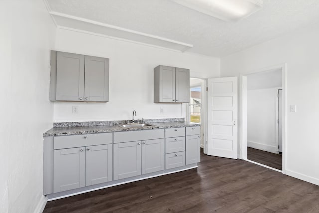 kitchen with dark wood-style floors, baseboards, a sink, and gray cabinetry