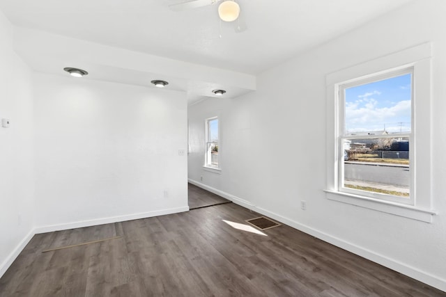 empty room featuring dark wood-style floors, visible vents, baseboards, and a ceiling fan