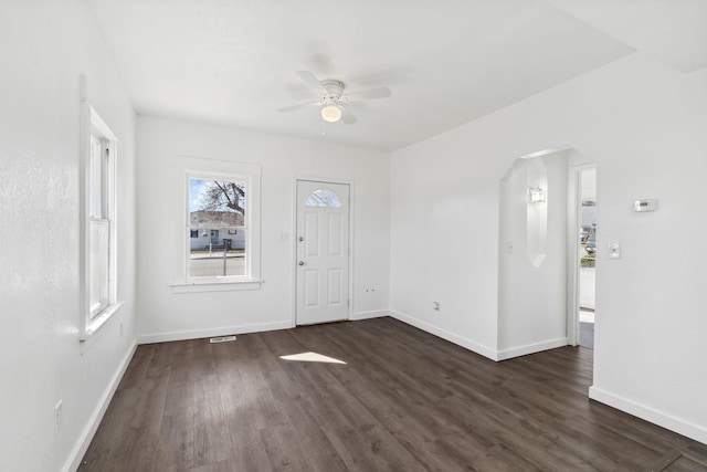 entryway with arched walkways, dark wood-style flooring, a ceiling fan, and baseboards