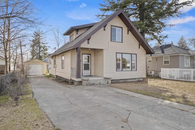 view of front of property featuring driveway, an outdoor structure, fence, and a detached garage