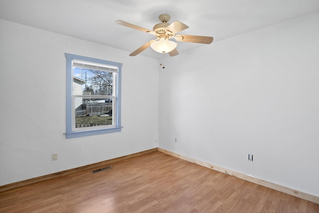 unfurnished room with ceiling fan, light wood-type flooring, visible vents, and baseboards