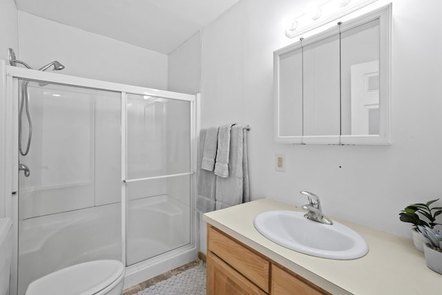 full bathroom featuring a stall shower, vanity, and toilet