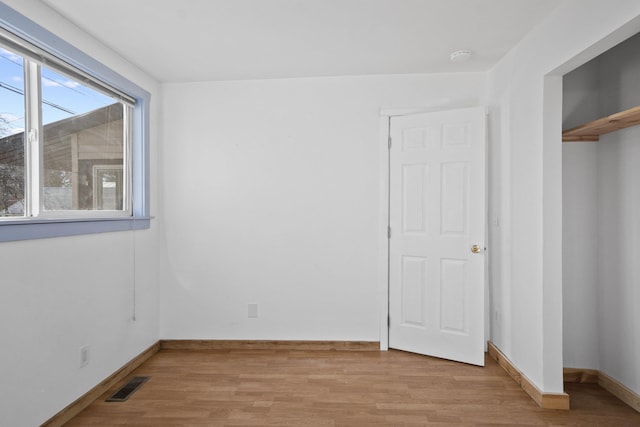 spare room featuring light wood-style flooring, visible vents, and baseboards