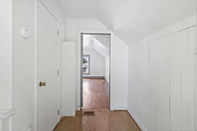 corridor featuring lofted ceiling, hardwood / wood-style flooring, baseboards, and visible vents